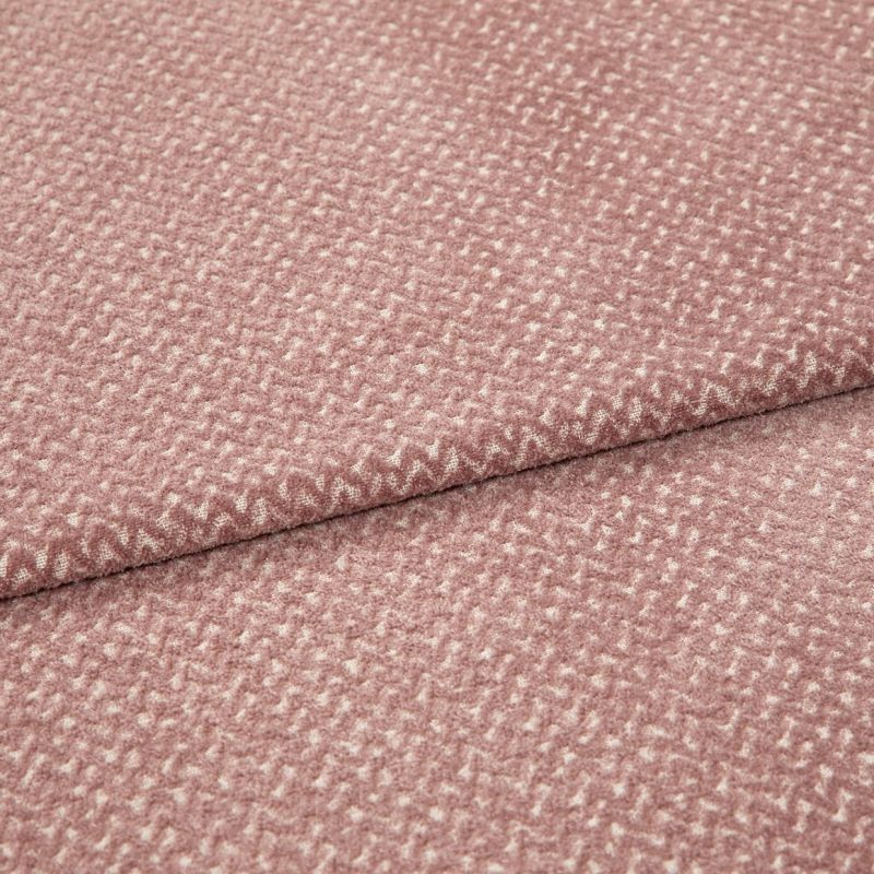 Textured woven upholstery fabric, dusty rose with small creamy fleck pattern, folded in two layers; lying flat on a neutral surface under soft, diffuse studio lighting for detail display.