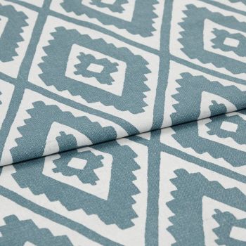 Woven fabric with teal-and-white serrated diamond print, folded along the center; lying flat in a close-up studio view with soft, even lighting.