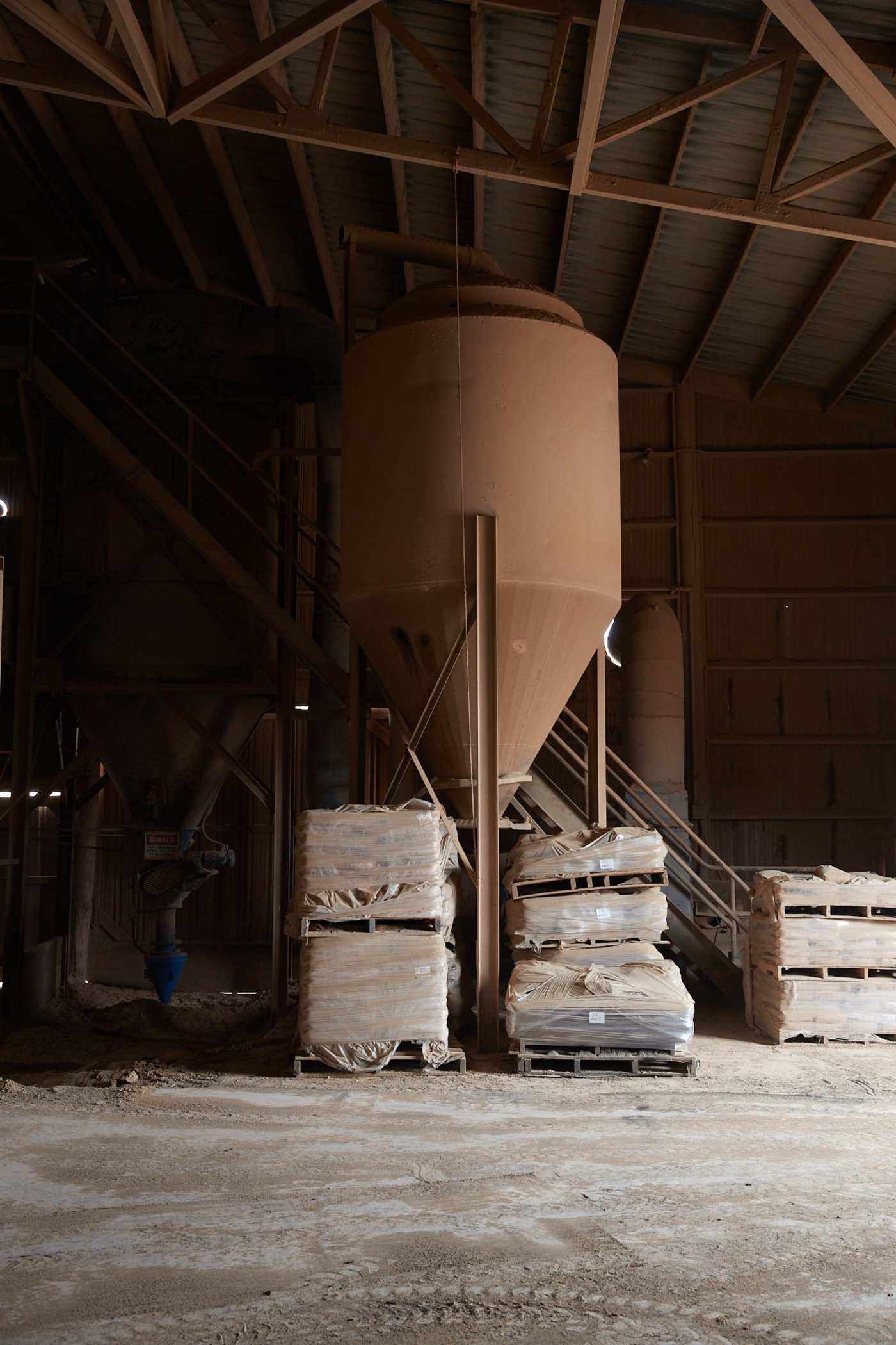 several pallets of material in a dusty tile warehouse.