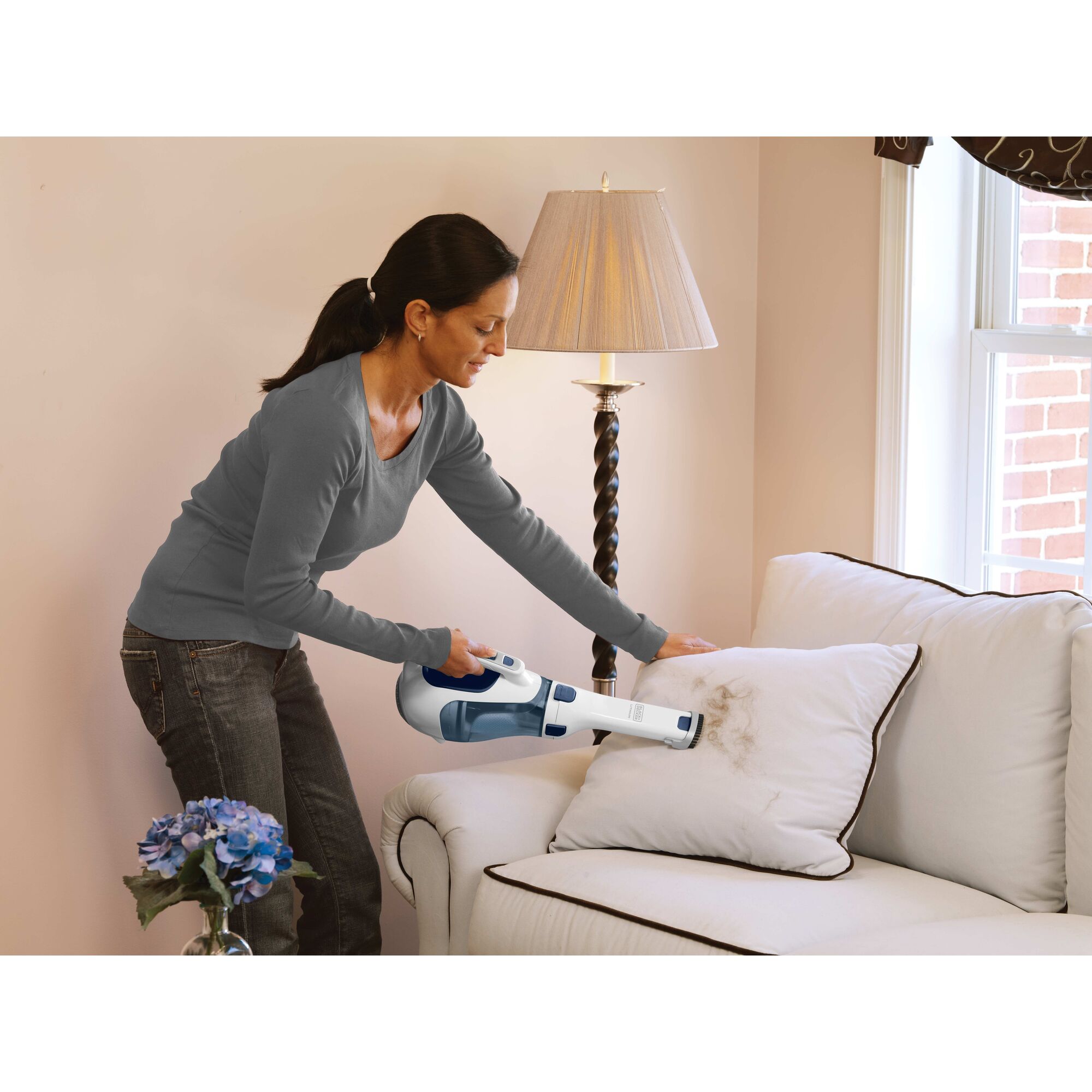 Woman cleaning sofa cushions with the BLACK+DECKER dustbuster