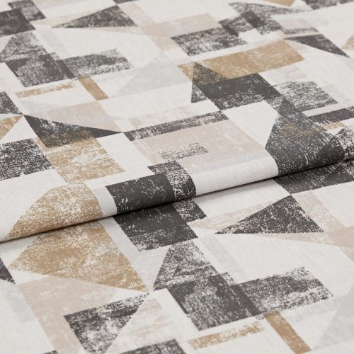 Folded textile sample with distressed geometric printâ€”overlapping triangles and rectangles in beige, tan and charcoal on off-whiteâ€”laid flat with a visible central fold under soft studio lighting.