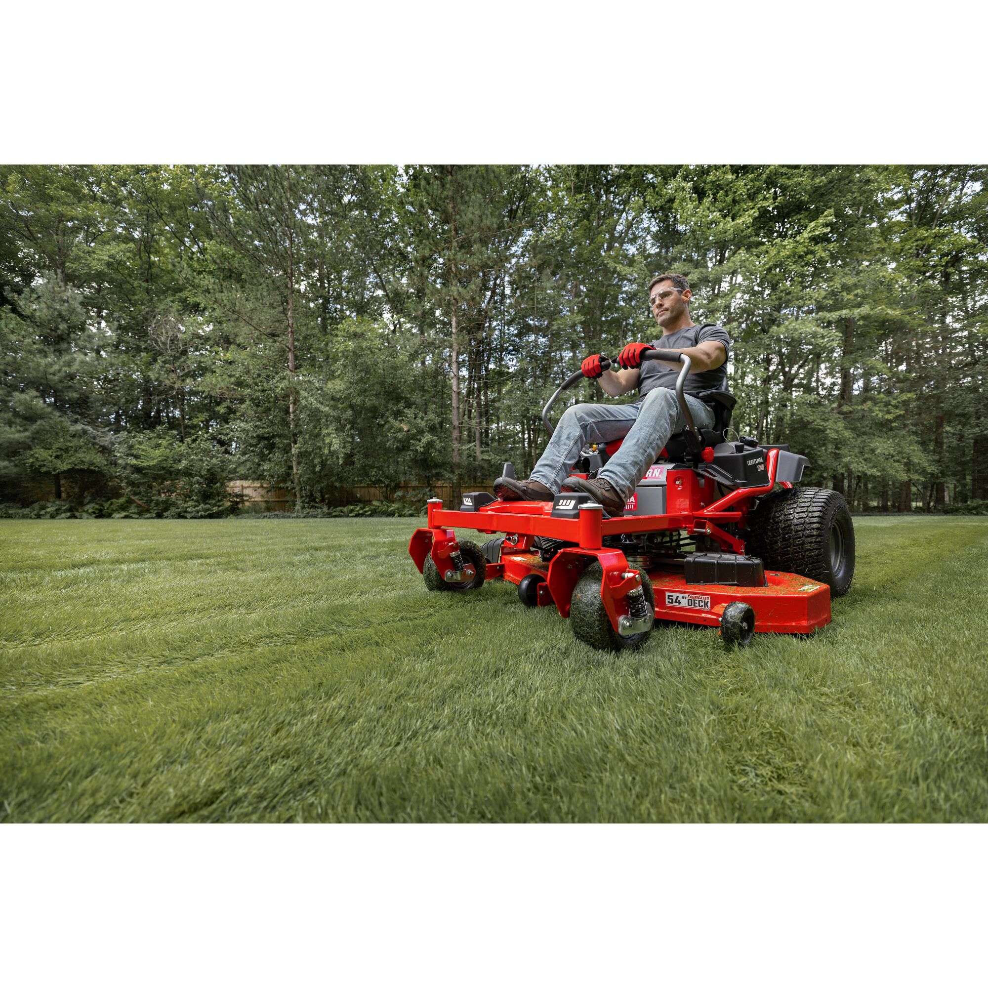 CRAFTSMAN Z7600 Gas Zero-Turn Mower mowing grass with wooded area in the background