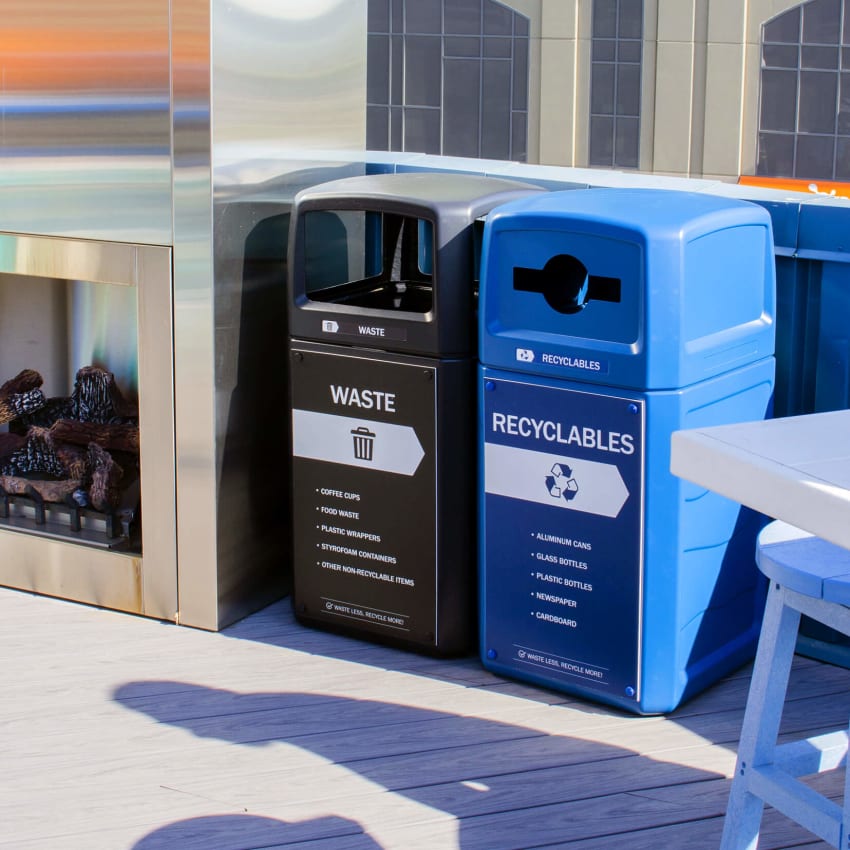 double waste and recyclables bins outside at a bar beside an outdoor fireplace