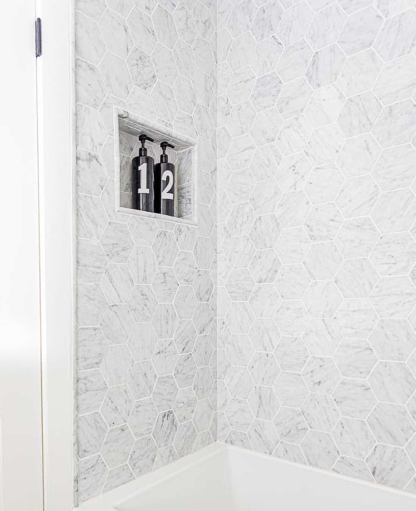 a bathroom with white tile and a number on the wall.