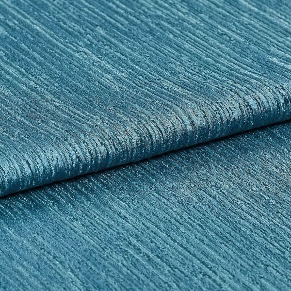 Teal ribbed fabric (folded), showing horizontal raised ridges and woven sheen; folded layers lie against each other in a close-up studio shot with even lighting, emphasizing texture and subtle metallic shimmer.