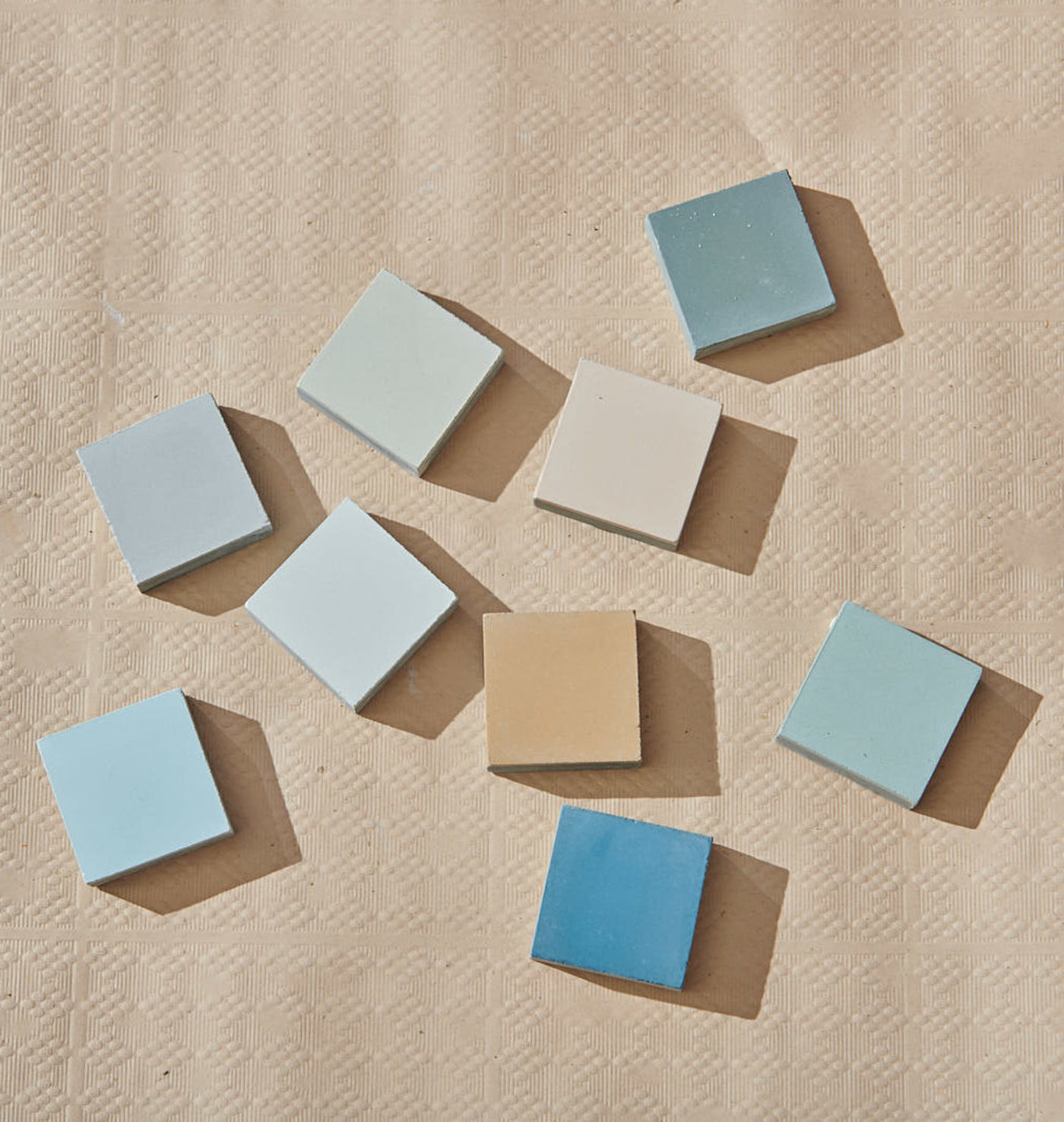 a group of multicolored tile chips scattered on a beige surface.