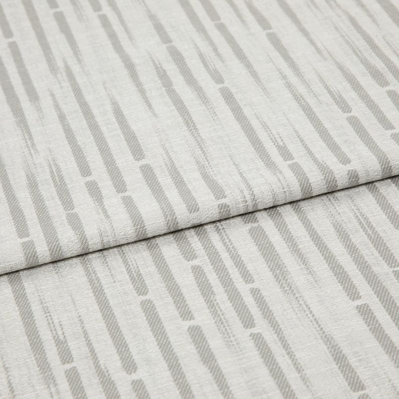 Light-gray patterned fabric, folded in overlapping panels, displaying vertical rounded dashes; close-up on textured linen-like material under soft, even lighting.