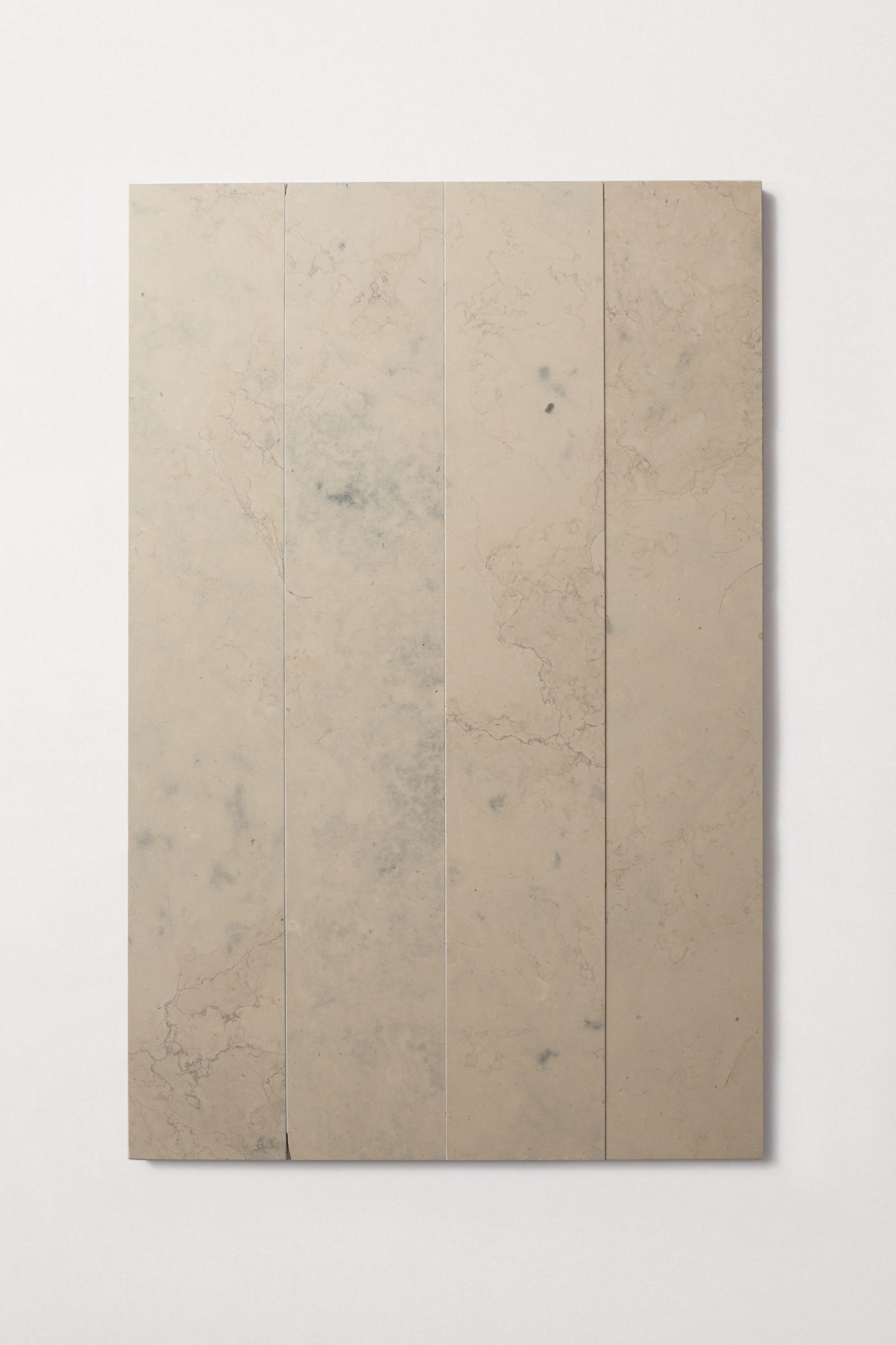 four beige limestone tiles on a white surface.