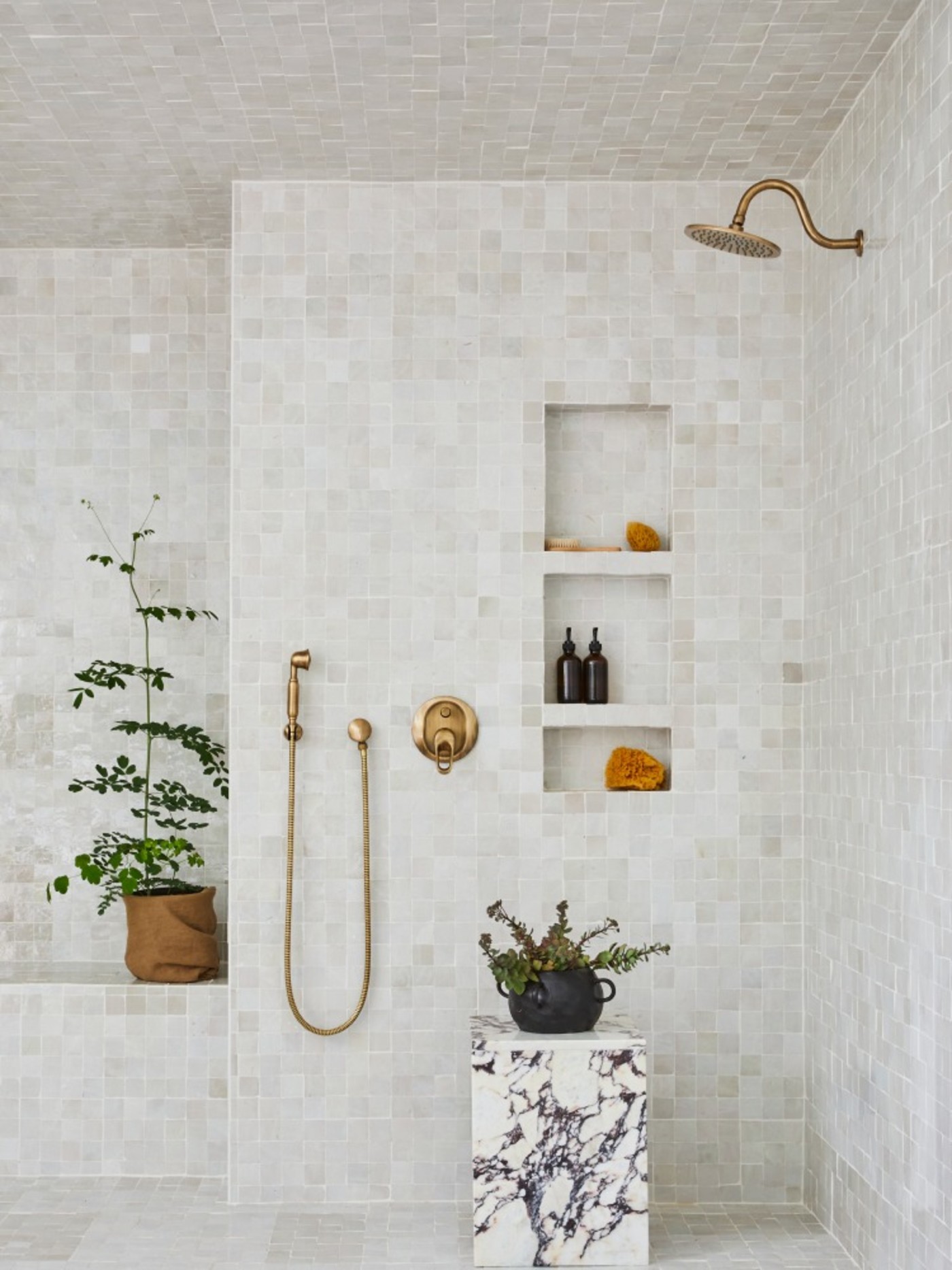 a white tiled shower with a potted plant.