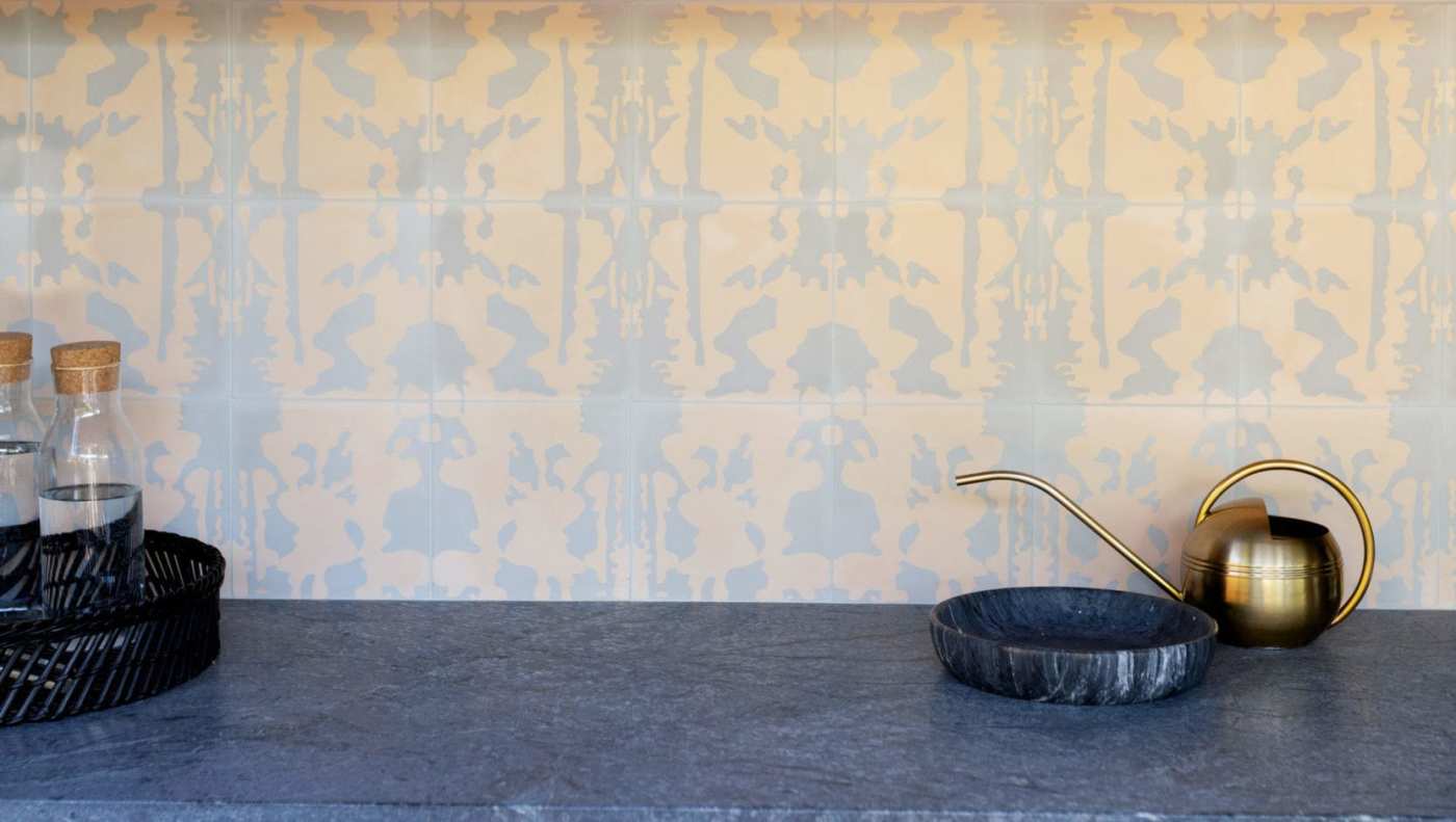 a kitchen counter with a brass tea pot and and glass bottles of water.