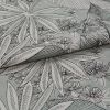 Folded floral-patterned fabric with leaf and flower print positioned diagonally, layered and partially overlapped; black outlined botanical motifs on a pale mint background, photographed close-up in soft lighting.
