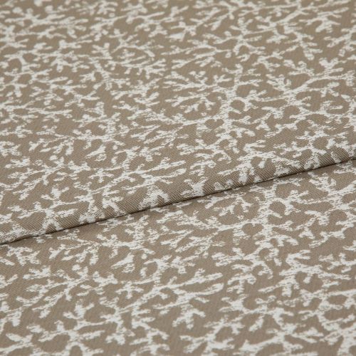 Beige woven fabric with a white, branch-like pattern folded across itself, shown close-up on a flat surface under soft, even lighting.