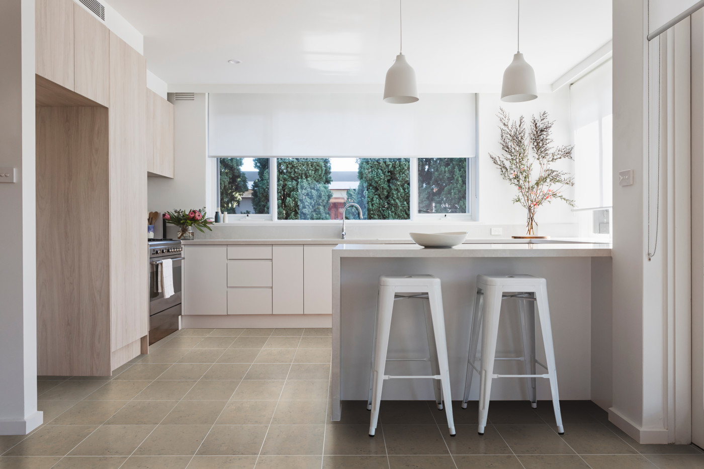 a kitchen with a grey tile floor and stools.