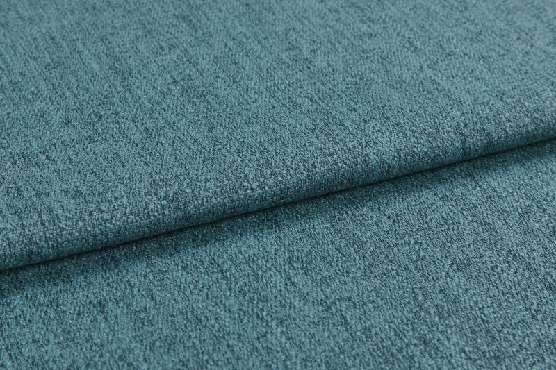Teal textured upholstery fabric, folded into overlapping layers with visible weave and nap; lying flat as a close-up sample under soft diffuse lighting, showing subtle color variation.