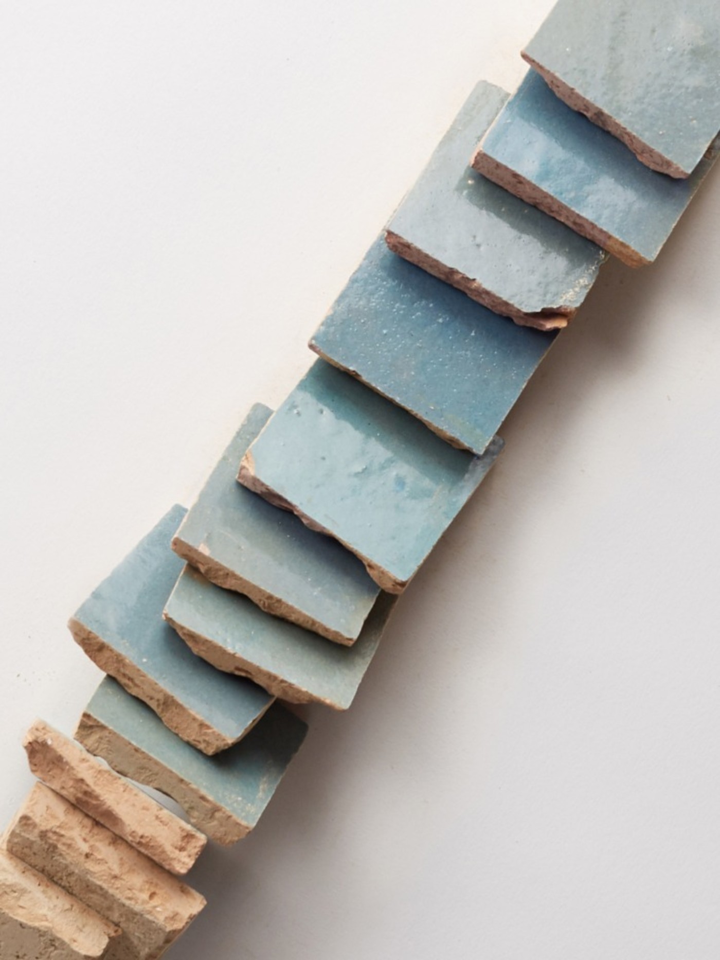 a stack of blue ceramic tiles on a white surface.