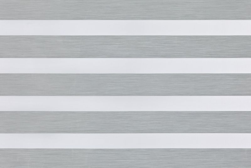 A dual-layer zebra roller blind with alternating opaque white and sheer gray textured horizontal bands across the window; filtering and diffusing daylight while partially blocking view; neutral indoor lighting.