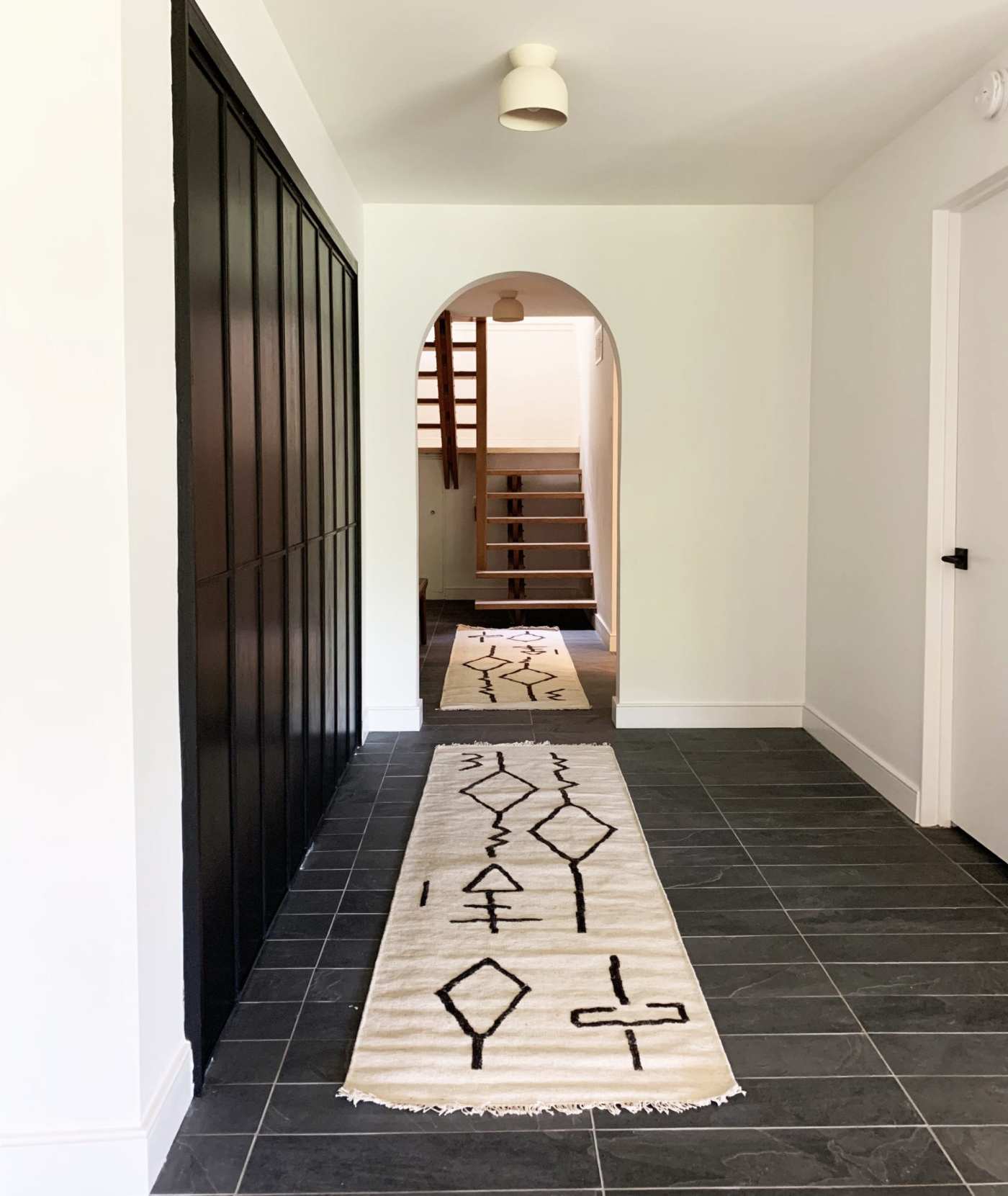 a tiled hallway with a black and white rug.