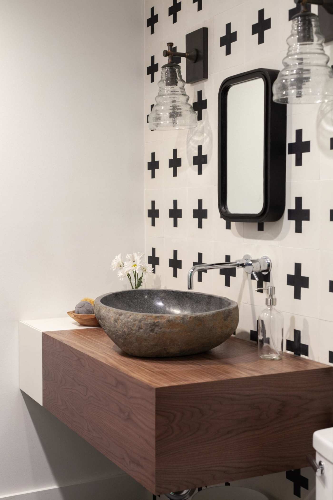 a bathroom with a stone sink and white and black tiled backsplash.