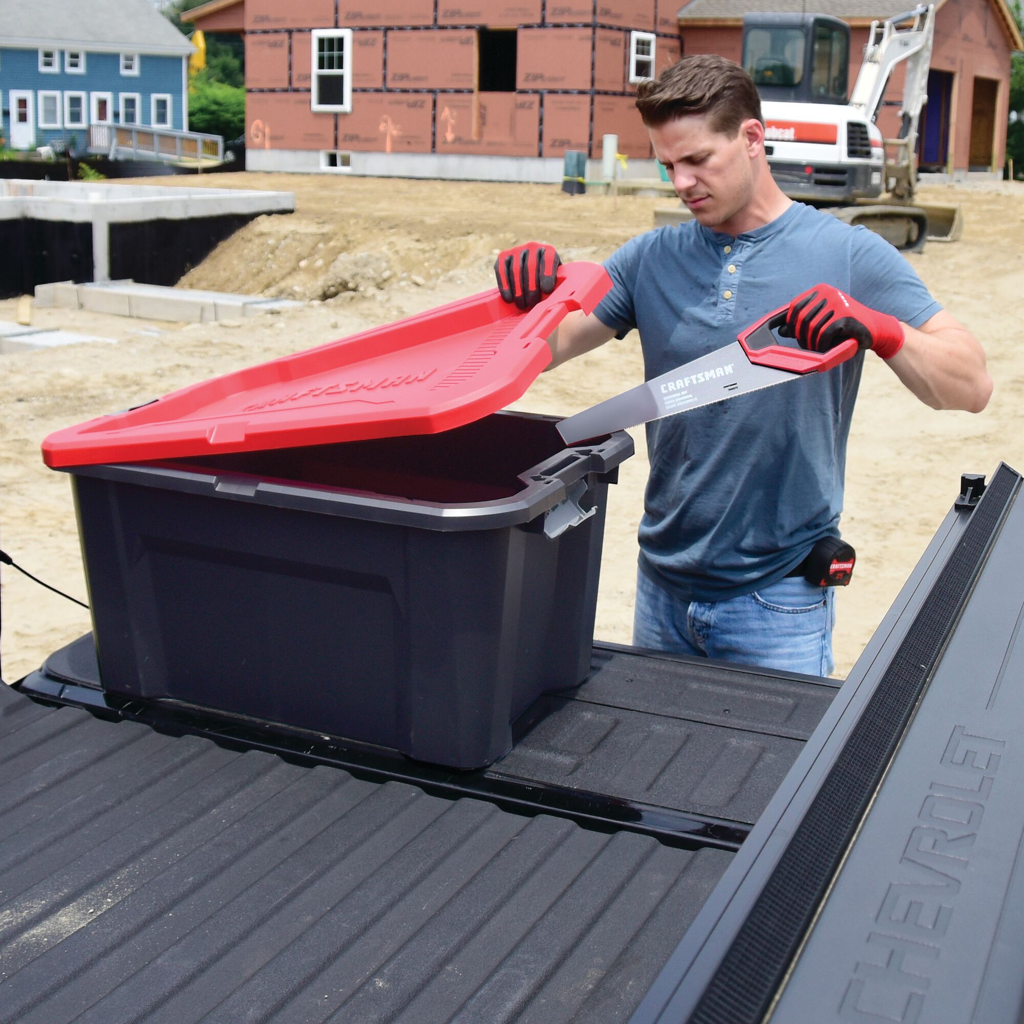 30 Gallon latching tote being used by a person to store tools.