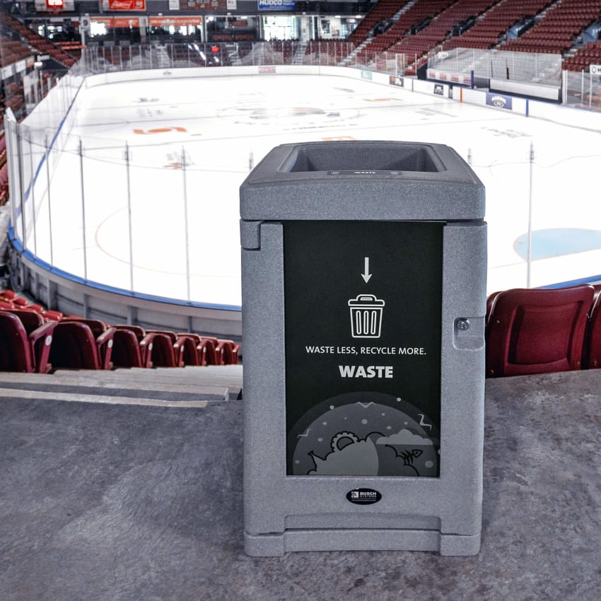 grey plastic waste container with large body signs and locking door sitting inside a hockey arena