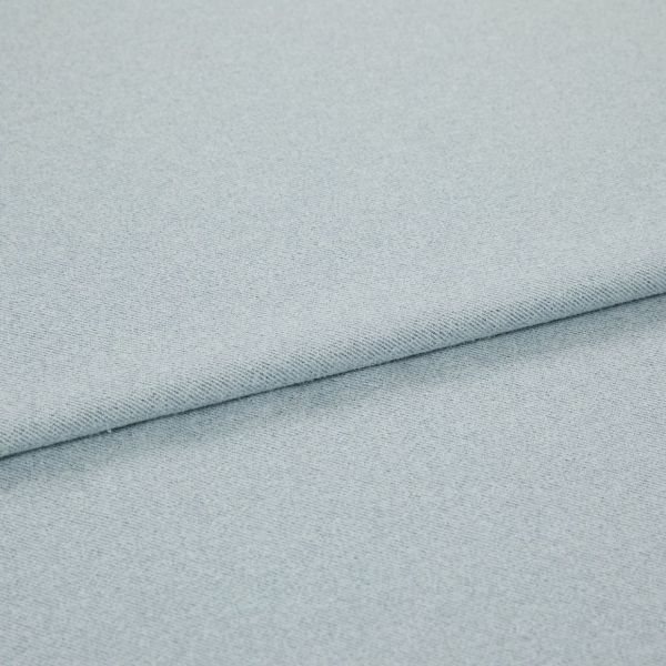 Pale blue woven fabric folded into overlapping layers; diagonal fold runs across frame, showing fine twill-like weave and subtle speckling under soft, even studio lighting.