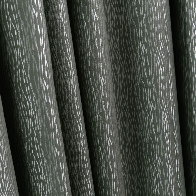 Heavy dark green patterned curtains with vertical folds and subtle silver streaks, closed and hanging in tight pleats, indoors under soft light, close-up with no visible view.