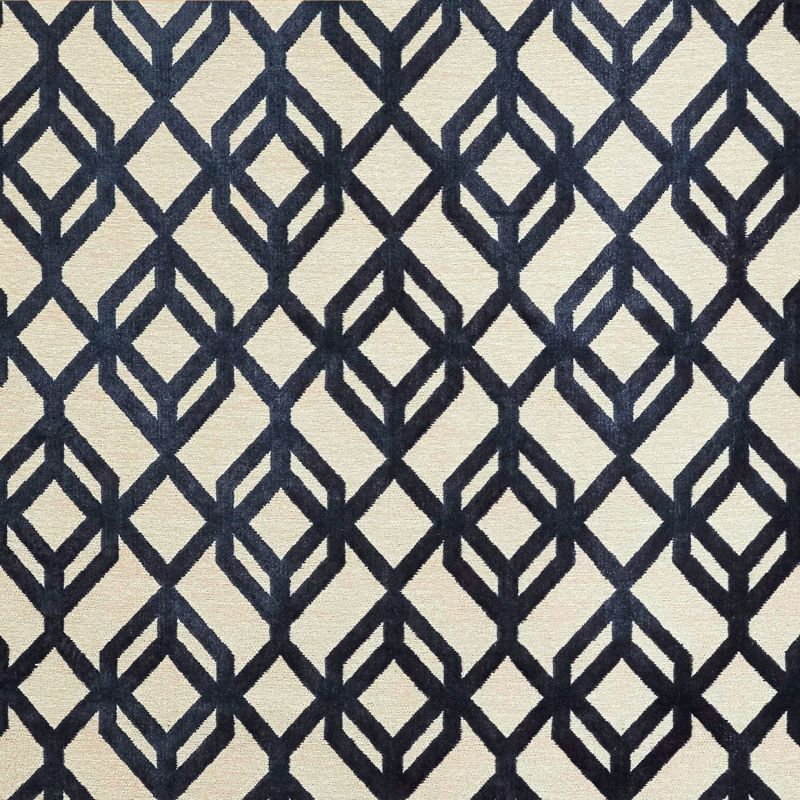 A beige rectangular rug with bold navy geometric diamond-lattice pattern lies flat (object), displayed as a close-up sample (action) under neutral studio lighting with no surrounding room visible (context).