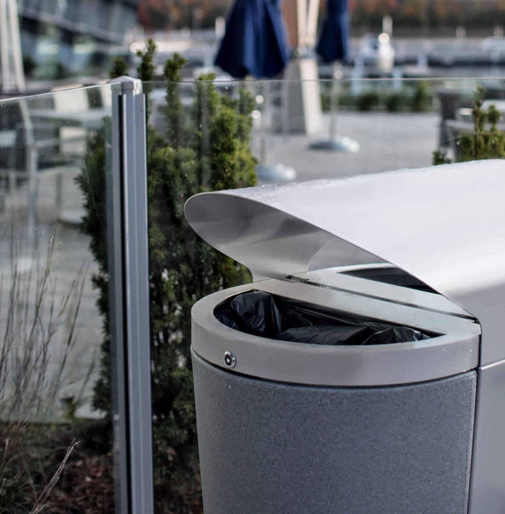 closeup image of a metal outdoor recycling and trash bin with locking liners and canopy top at a marina