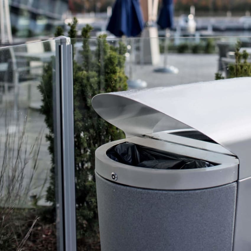 closeup image of a metal outdoor recycling and trash bin with locking liners and canopy top at a marina