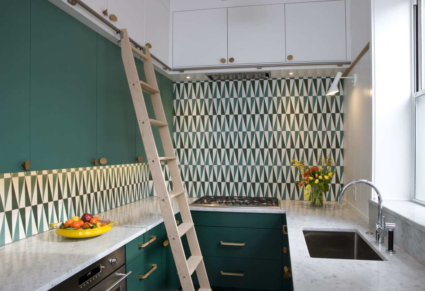 a green and white tiled kitchen with a ladder.