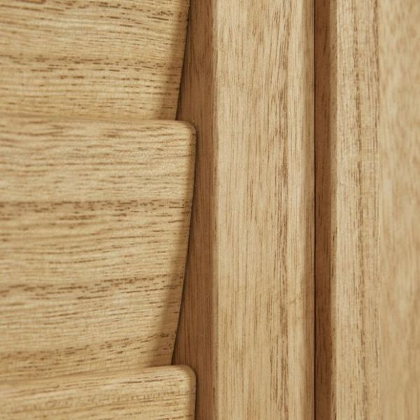 Light oak louvered shutter panel, close-up showing a slat and frame with visible grain; slats fitted and closed within the frame, warm interior lighting.