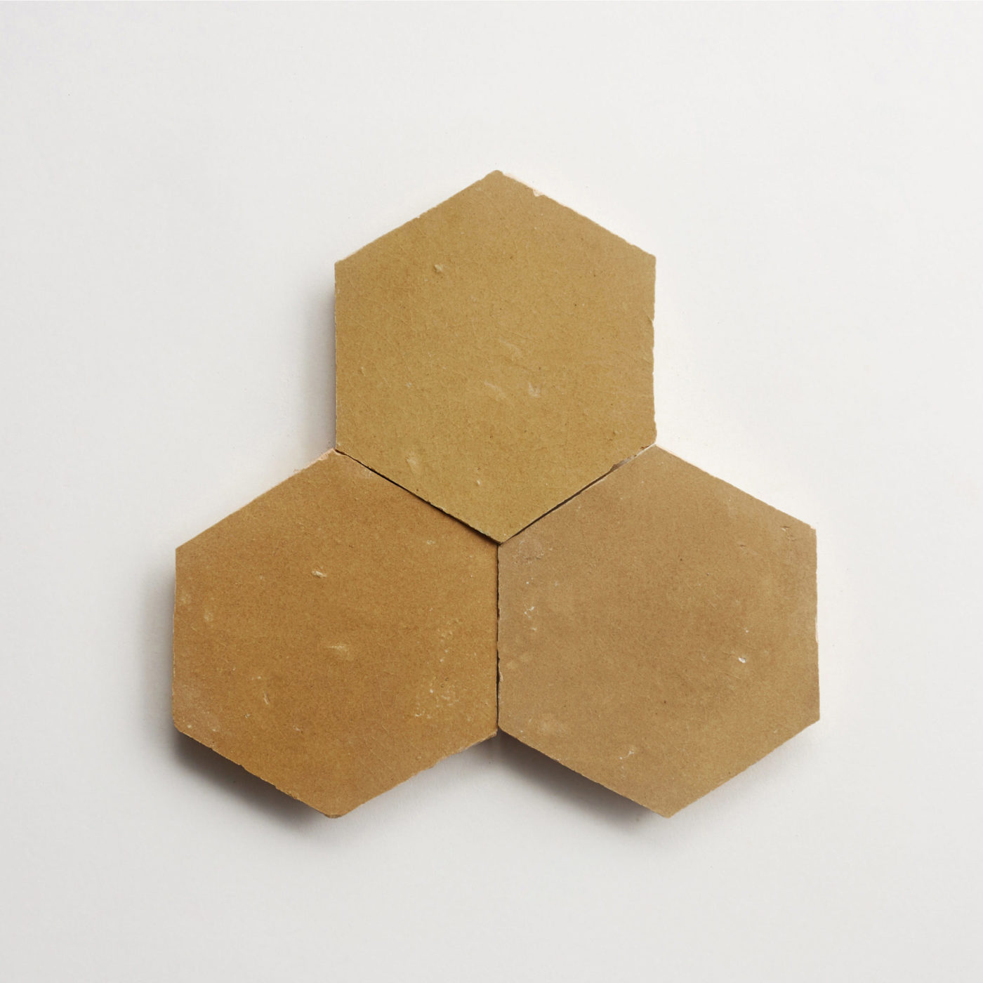 three brown hexagonal tiles on a white surface.