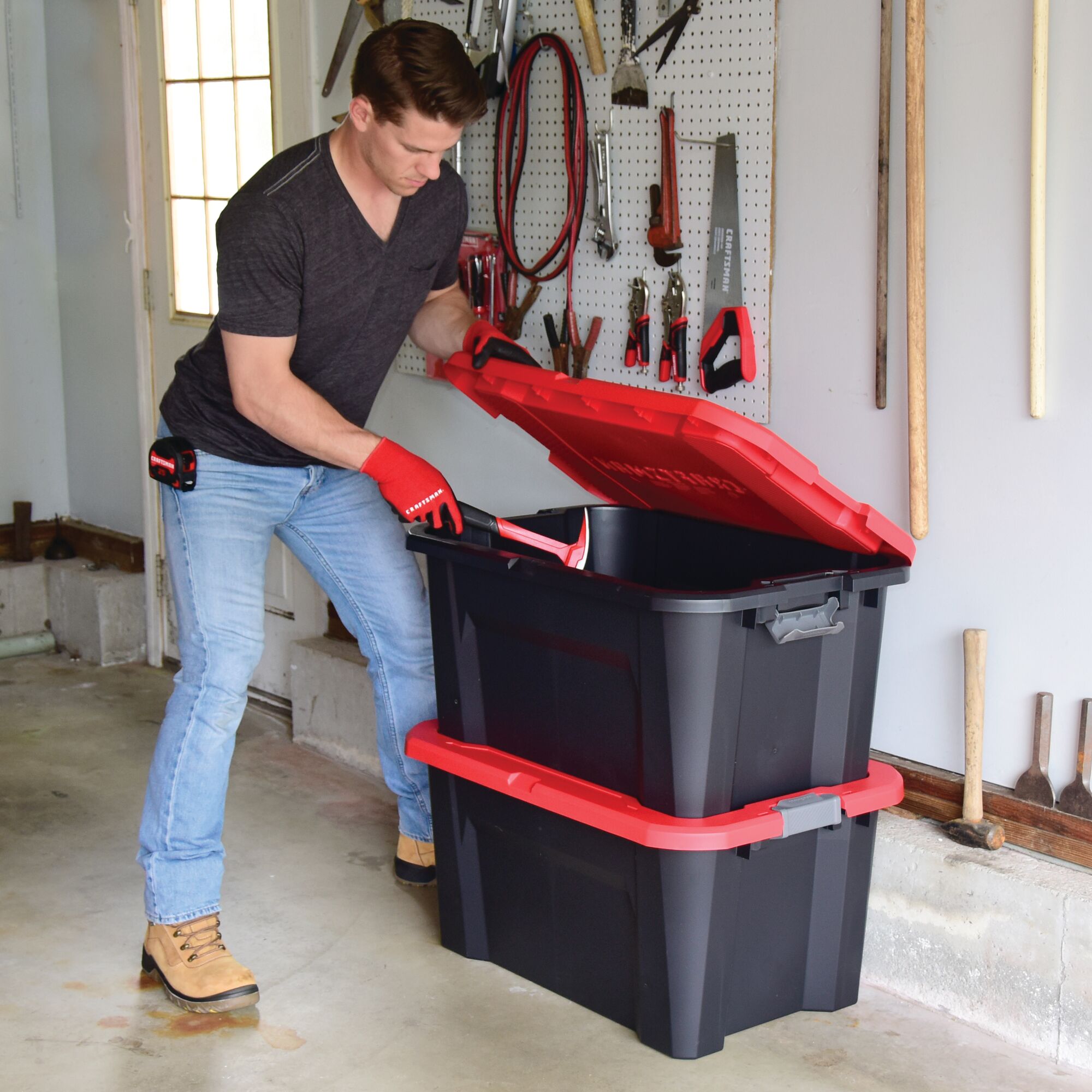 30 Gallon latching tote being used by a person to store tools.