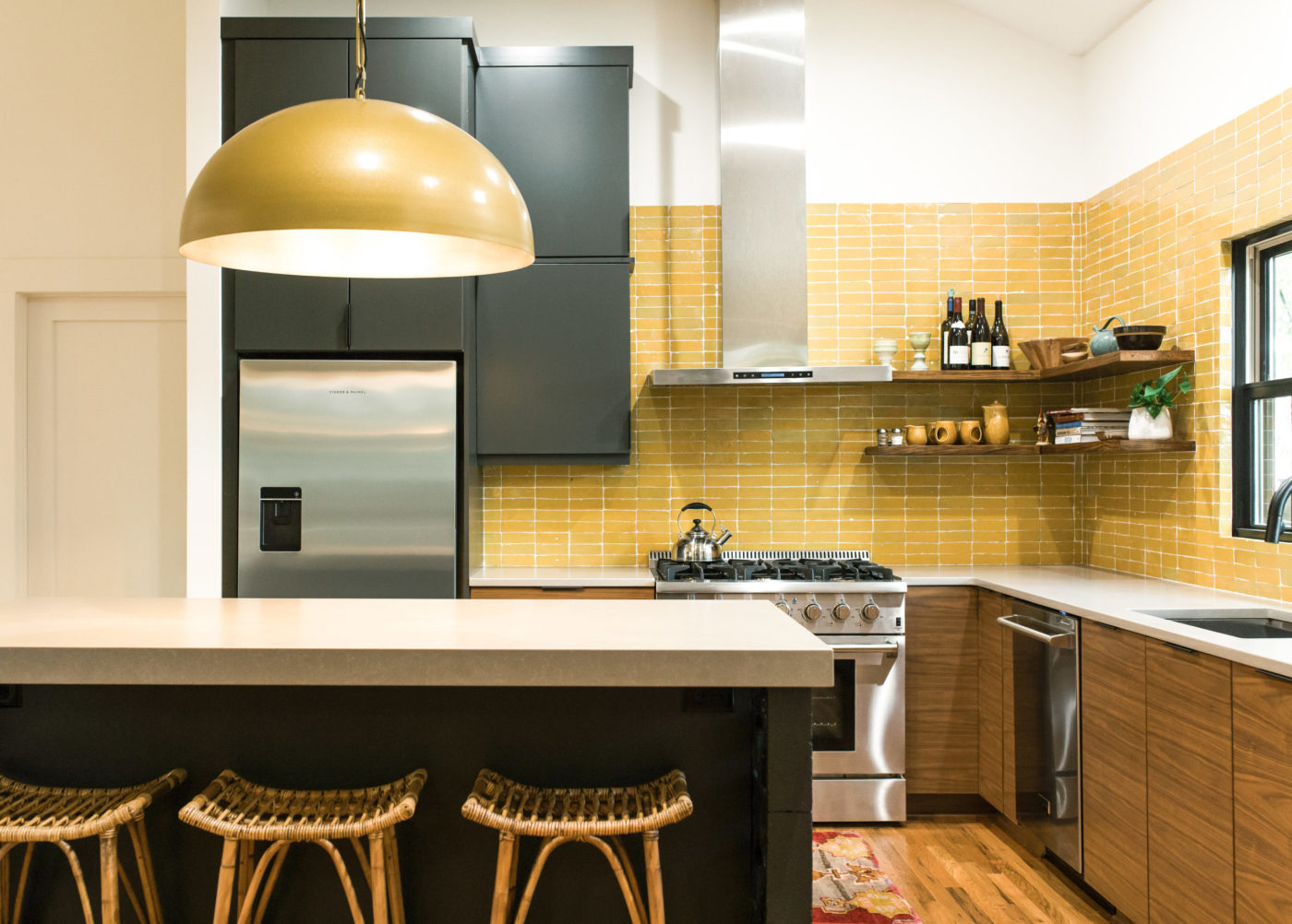 a kitchen with yellow tile backsplash and stools.