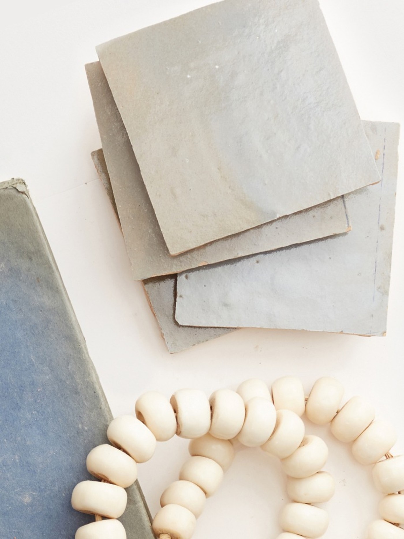 grey square tiles and stringed beads on a table.