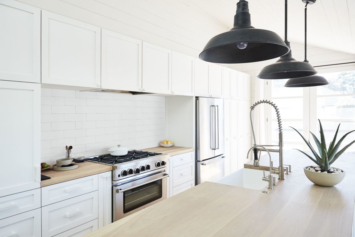 a kitchen with white cabinets and wooden counter tops.