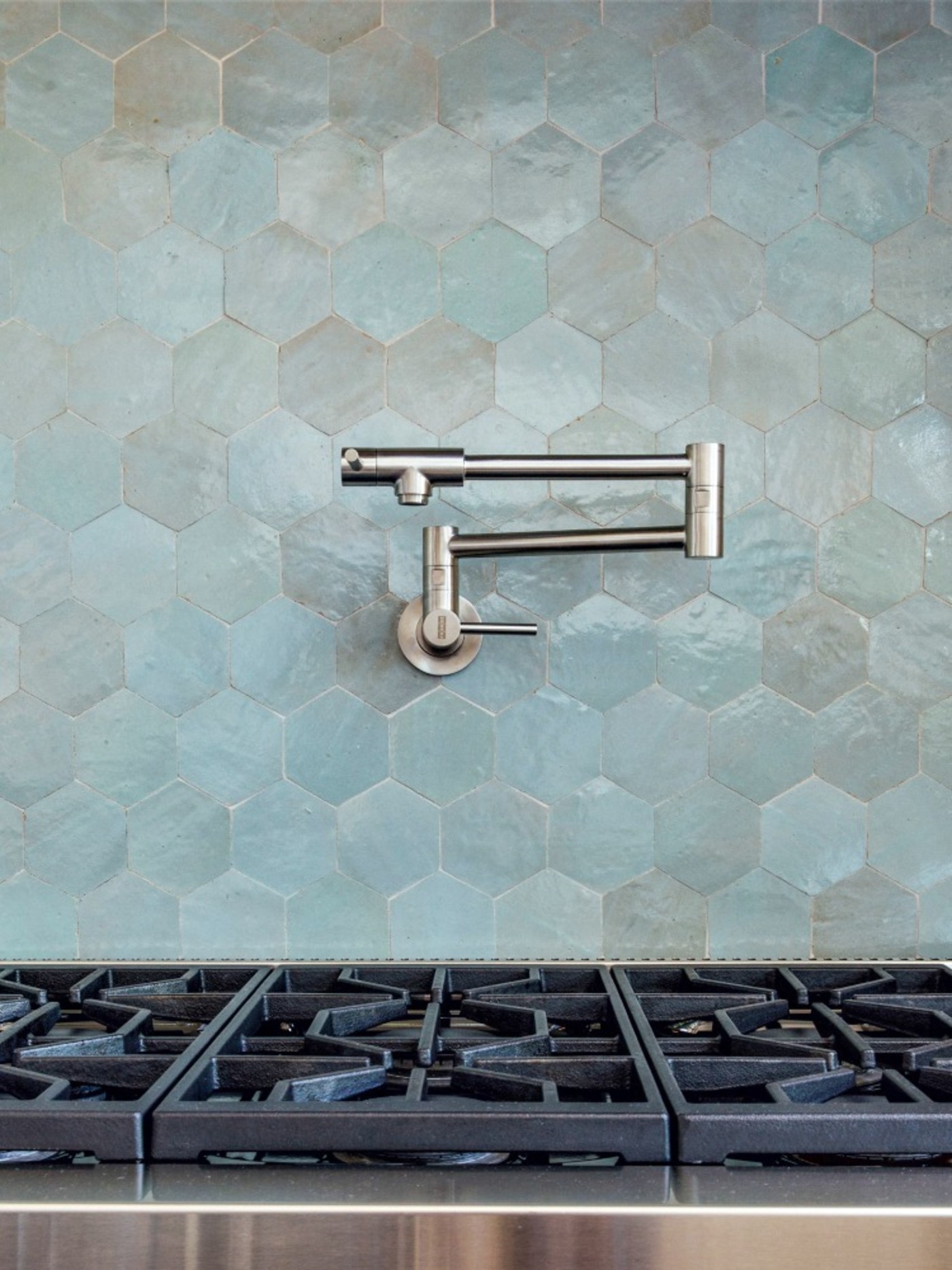 a faucet and counter with a blue tiled backsplash.