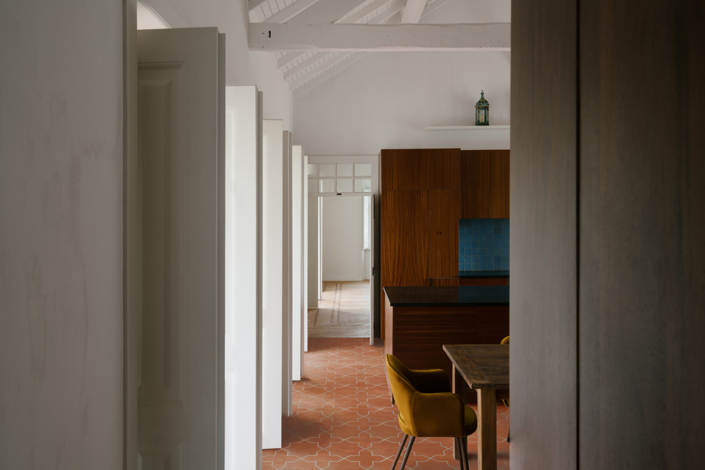 a kitchen with a wooden table and a red tile floor.