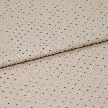 Beige woven fabric with regular small navy dash dots, folded once across center, lying flat on a neutral surface; close-up, even studio lighting highlighting its textured weave.