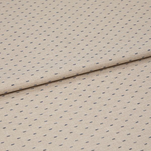 Beige woven fabric with regular small navy dash dots, folded once across center, lying flat on a neutral surface; close-up, even studio lighting highlighting its textured weave.