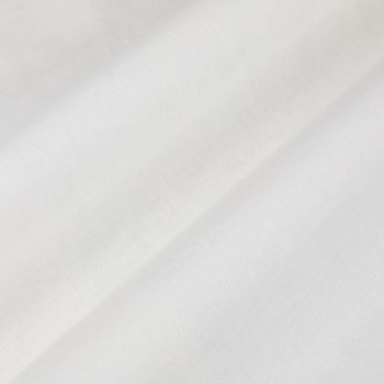 White fabric with a diagonal fold forming a soft shadowed ridge; light subtly diffused across its smooth woven texture in a bright, minimal interior.