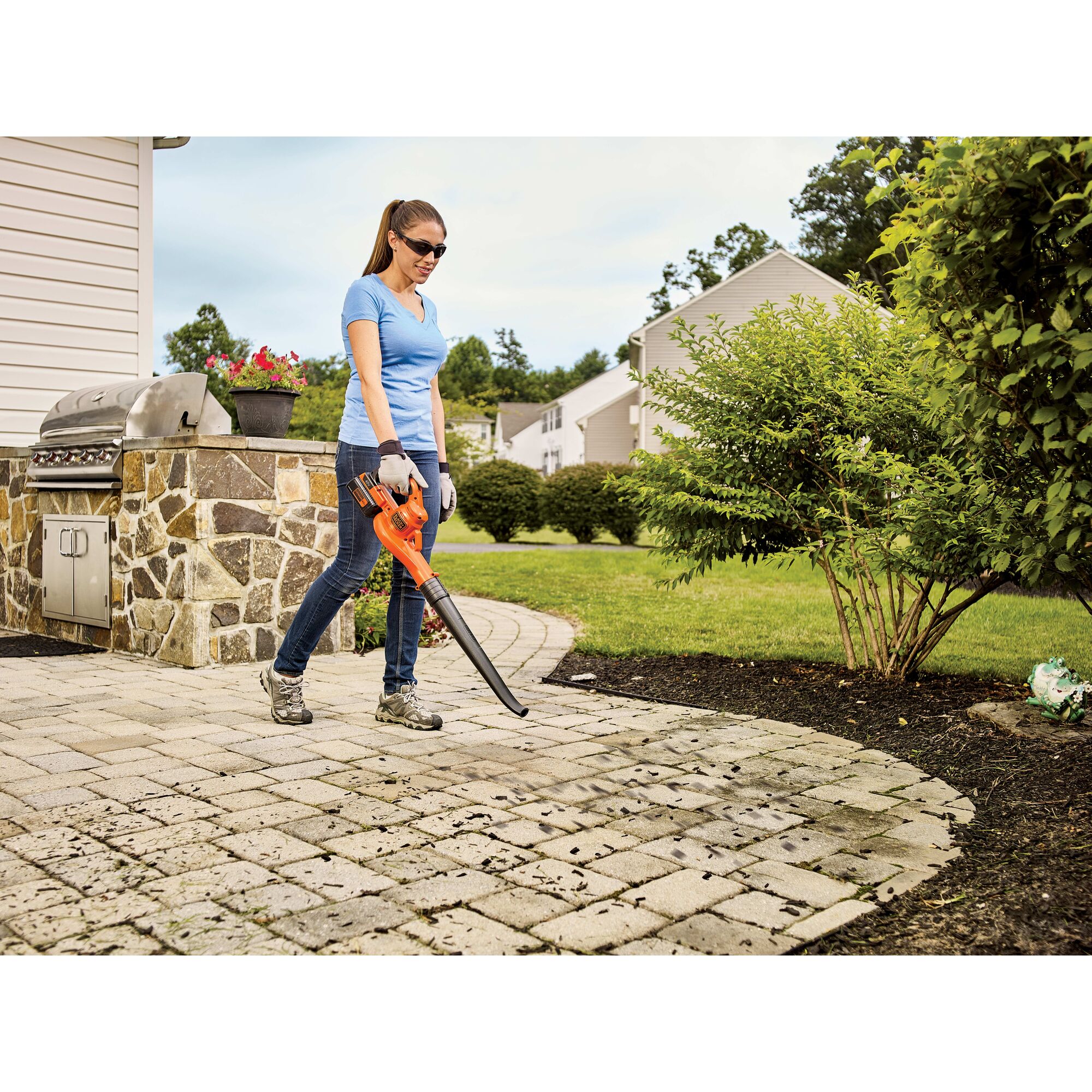 Woman using 40V Max Sweeper to clear debris from a stone patio.
