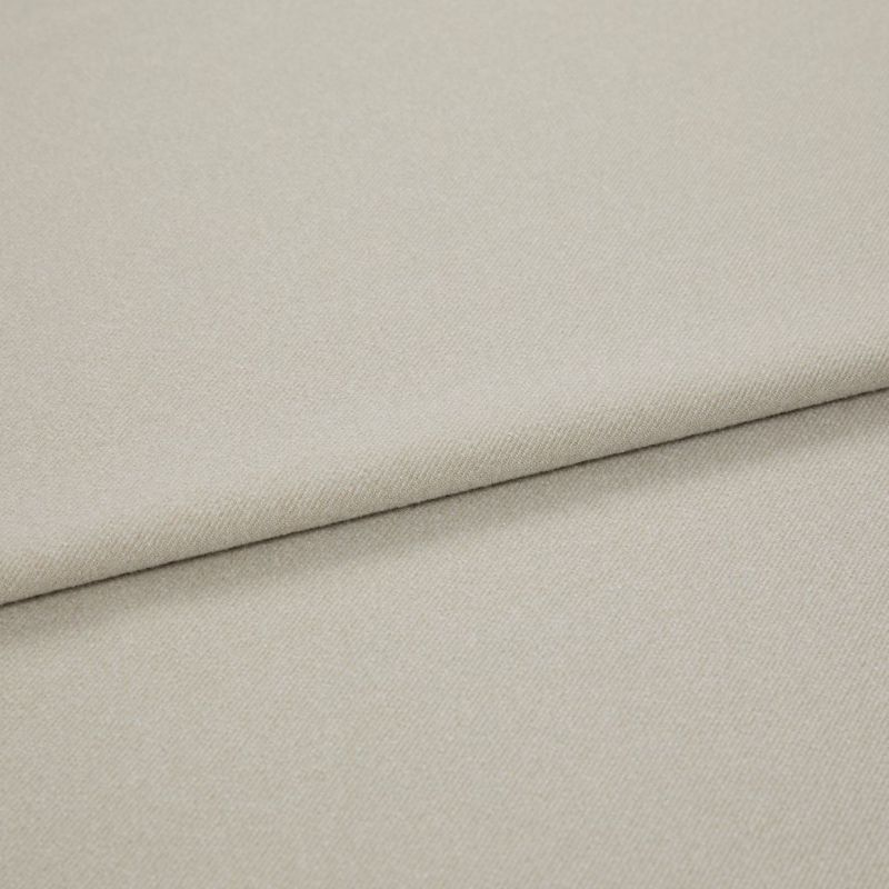 Beige woven fabric folded diagonally, overlapping to form a soft seam; close-up view with even, neutral lighting highlighting fine twill texture.