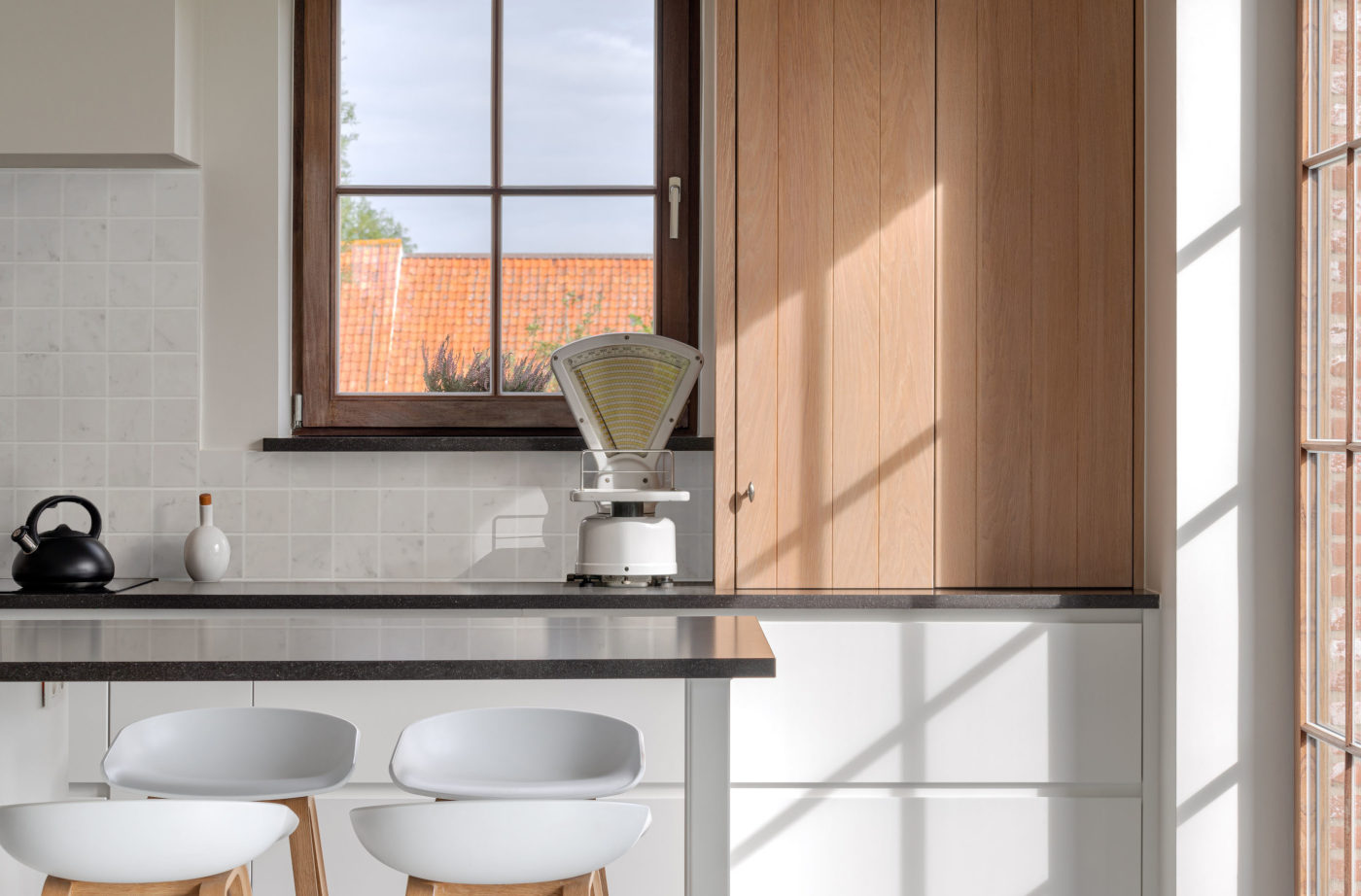 a white kitchen with wooden cabinets and stools.