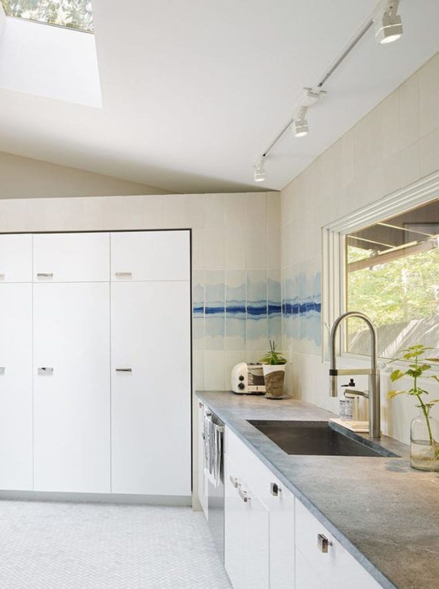 a kitchen with a skylight and white cabinets.