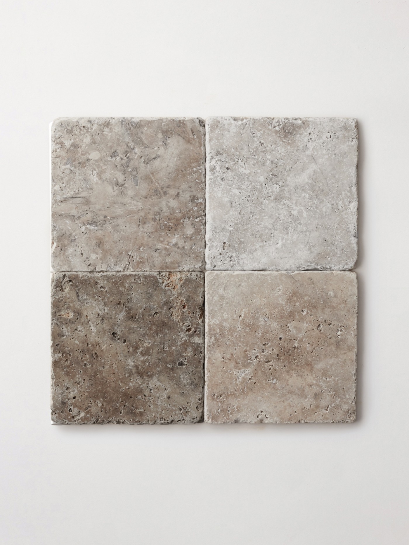 a set of four square, natural stone tiles on a white surface.