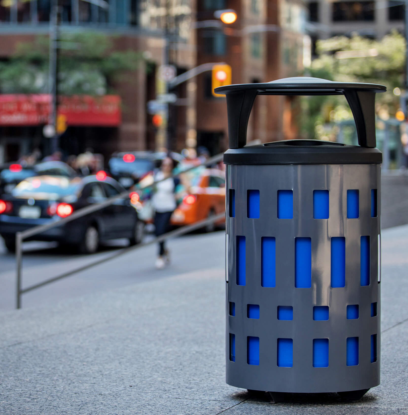 double outdoor waste and recycling bin with a grey powder coated steel body and black plastic canopy lid in a busy downtown street