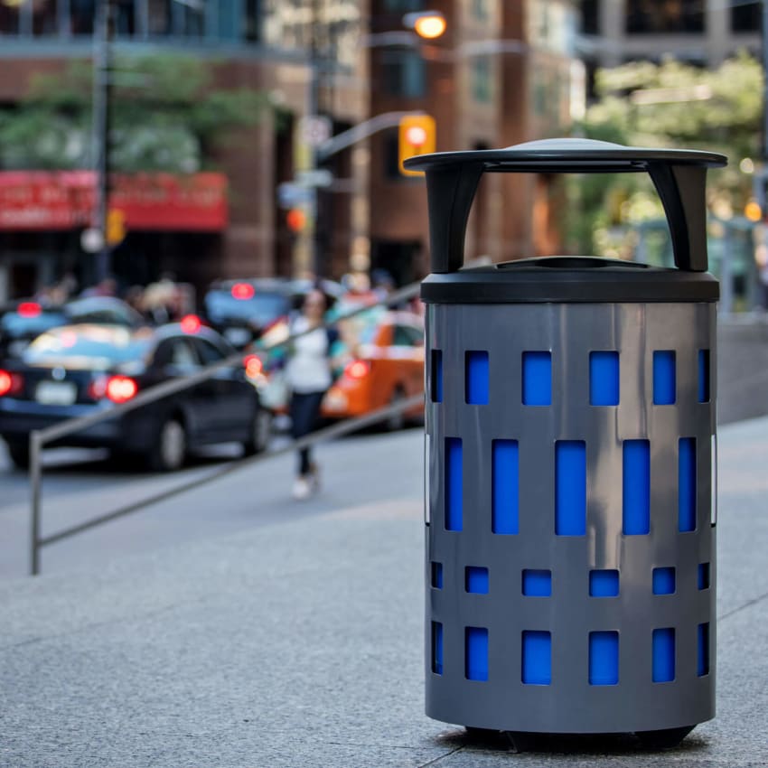 double outdoor waste and recycling bin with a grey powder coated steel body and black plastic canopy lid in a busy downtown street