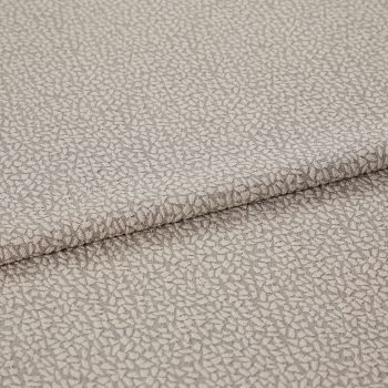 Beige jacquard-like upholstery fabric, folded over itself, displaying a dense small pebble motif; close-up studio-lit view highlighting subtle sheen, woven texture, and gentle drape.