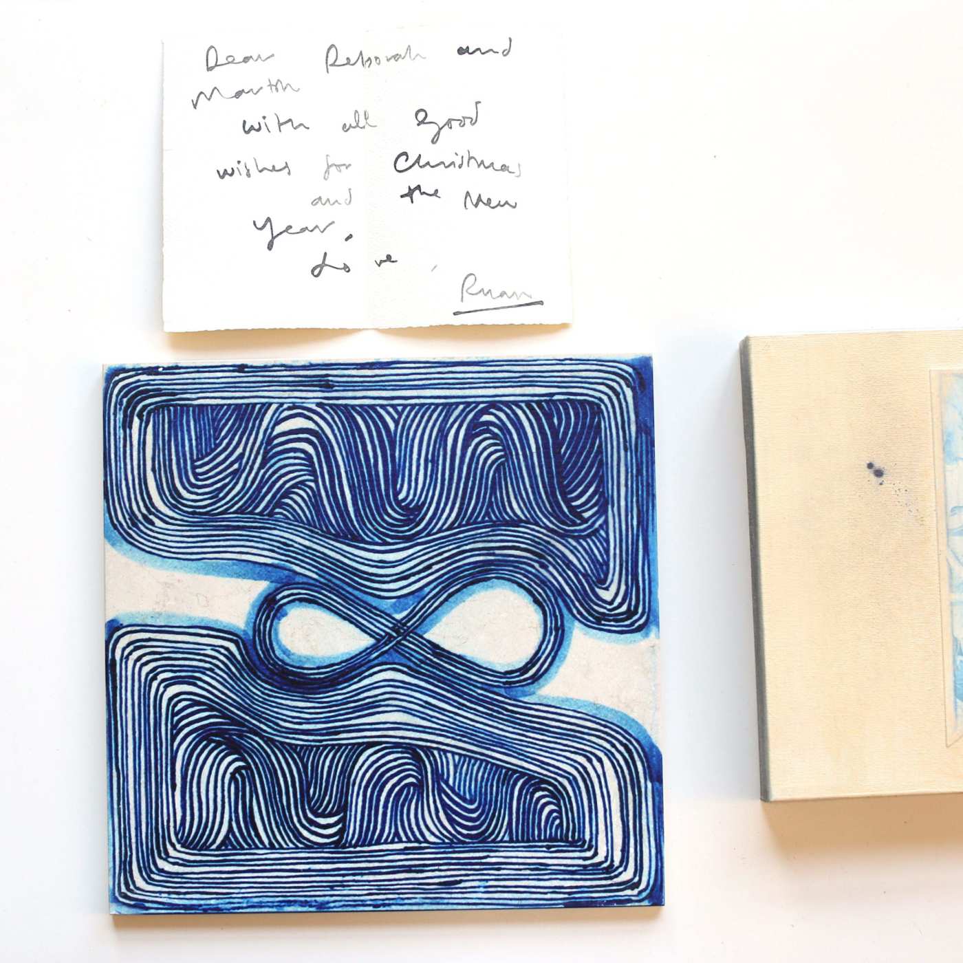 a blue piece of handpainted tile with handwritten notes next to it.